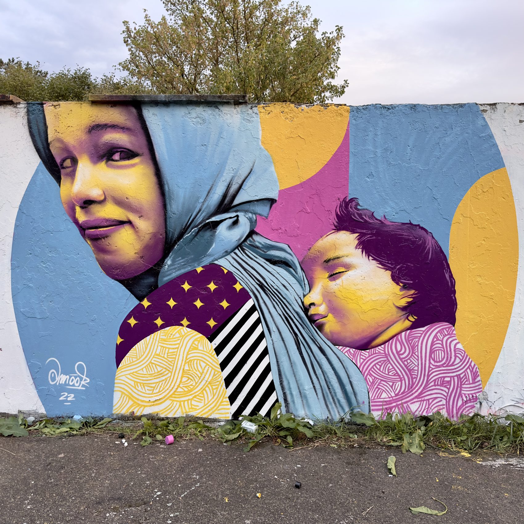 Fresque murale d'Amoor : une mère voilée et son enfant sur fond de motifs colorés